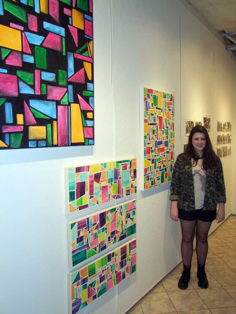 Elle Radan, FCLC’13, beside her paintings in the senior art exhibit. (Ludovica Martella/ The Observer)