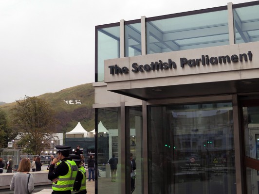 News media on Wednesday, Sept. 17, 2014 in Edinburgh gather around the Scottish parliament, while on the extinct volcano in the background Scottish independence advocates put up a huge sign urging a "Yes" vote. (Courtesy Claudia Himmelreich/McClatchy via MCT)